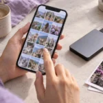 Человек просматривает фотографии на телефоне рядом с внешним накопителем