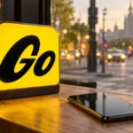 Android-смартфон рядом с подсвеченным официальным знаком Яндекс Go